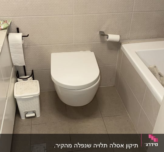אסלה תלויה ולחצן ניאגרה סמויה בחדר רחצה מרוצף ומחופה